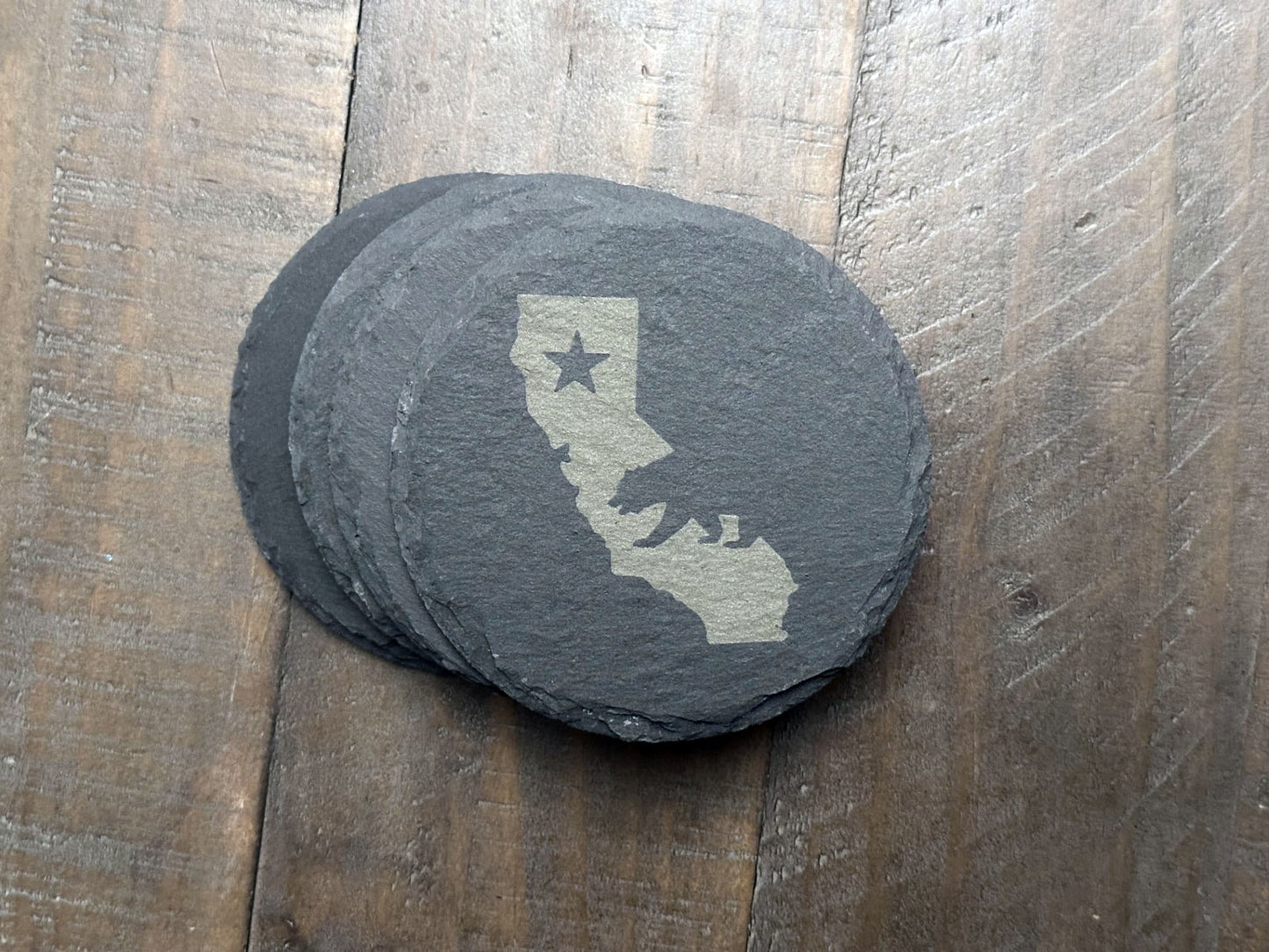 These California themed slate coasters are a real "bear" necessity to show off some state pride. Laser engraved with either the state's outline, lone star, and a grizzly bear or the California flag, they’re a bold way to keep your drinks in check. Made from durable slate, these coasters are both functional and stylish, making them a perfect addition to any home or as a gift for lovers of the Golden State.