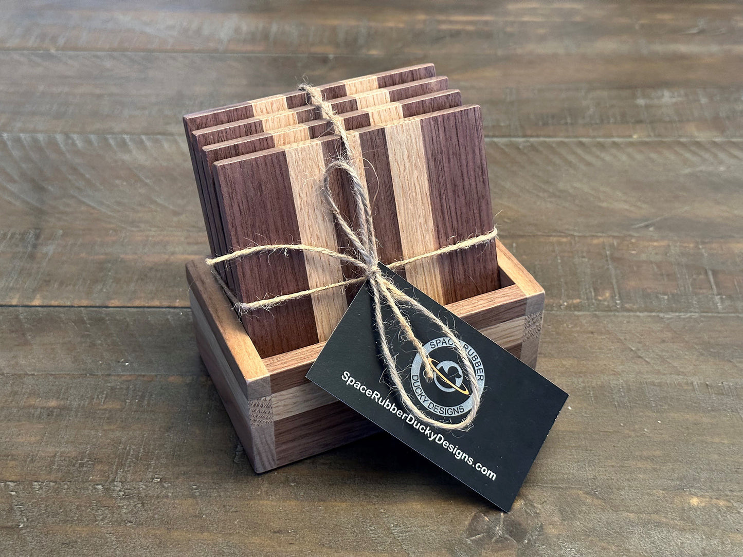 Enjoy a beverage while protecting your tabletops with these walnut and white oak hardwood coasters. Available in a set of 4 coasters and includes a custom holder. Each coaster is coated in polyurethane for water resistance and they have felt footpads to protect your surfaces. As a handmade wood product, there will be slight variation between the product you receive and the listed images.