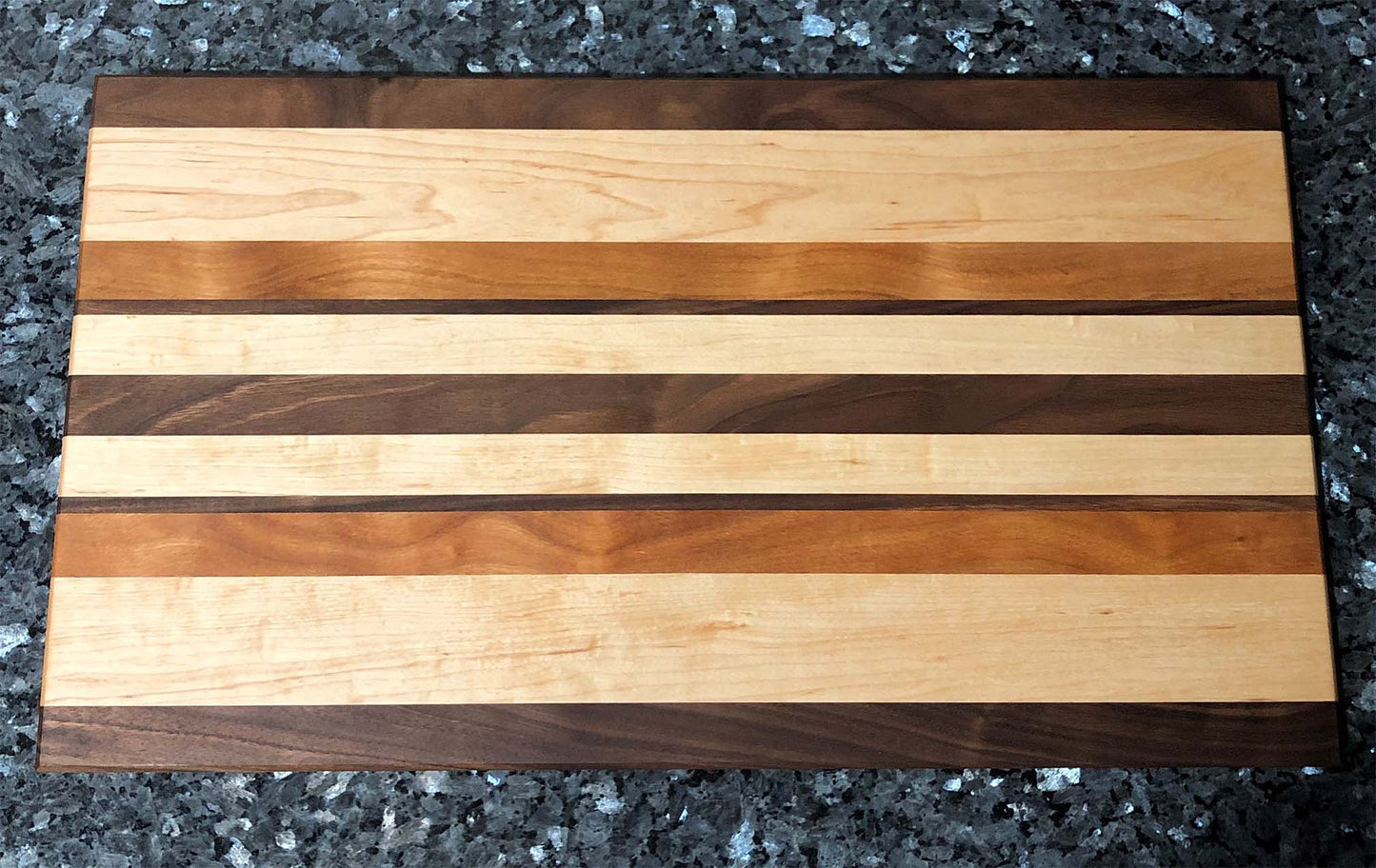 Long grain cutting board. Features black walnut, maple, cherry hardwoods.