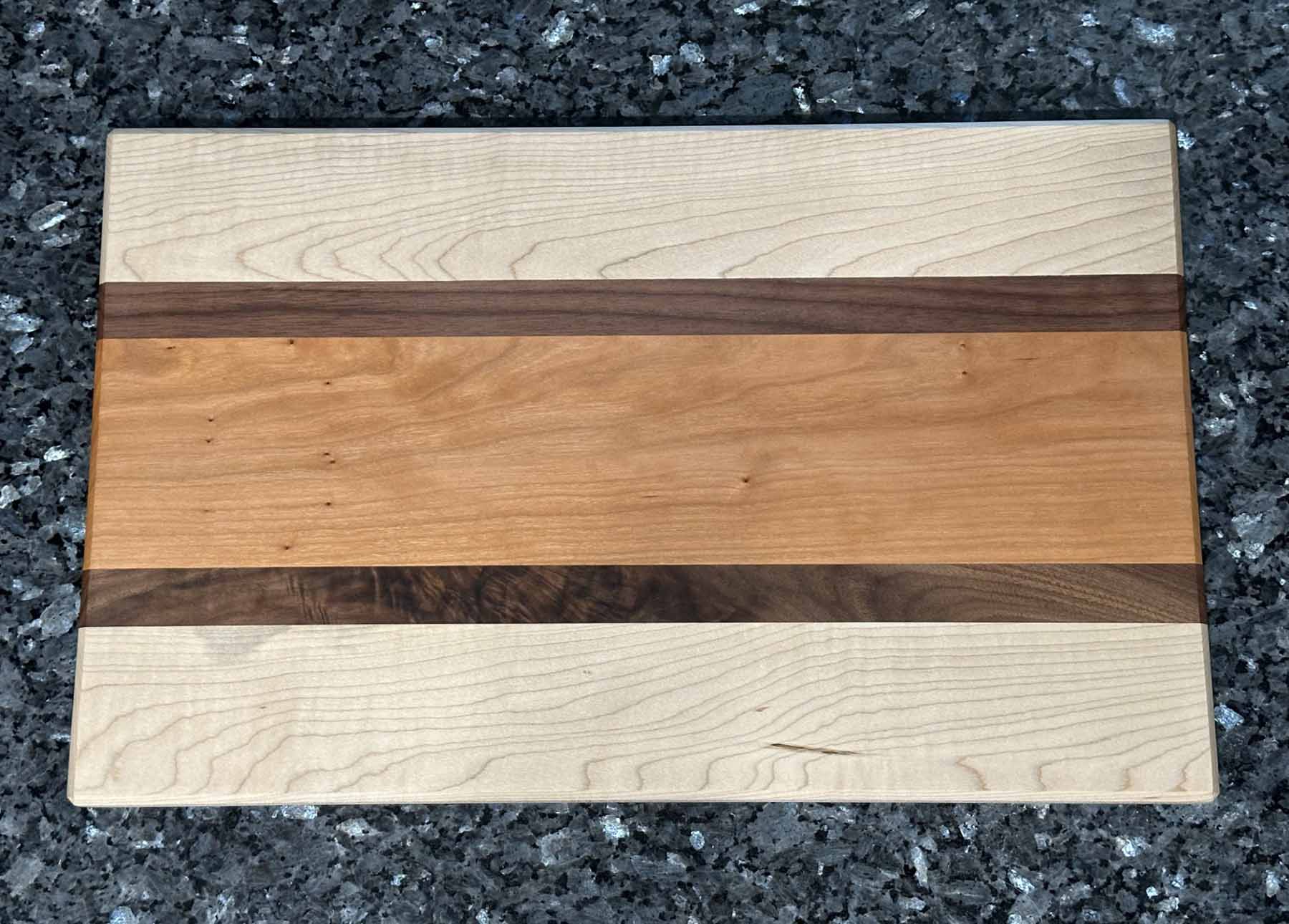 A combination of maple and cherry hardwoods with striking black walnut accents, this long grain cutting board blends function with style.