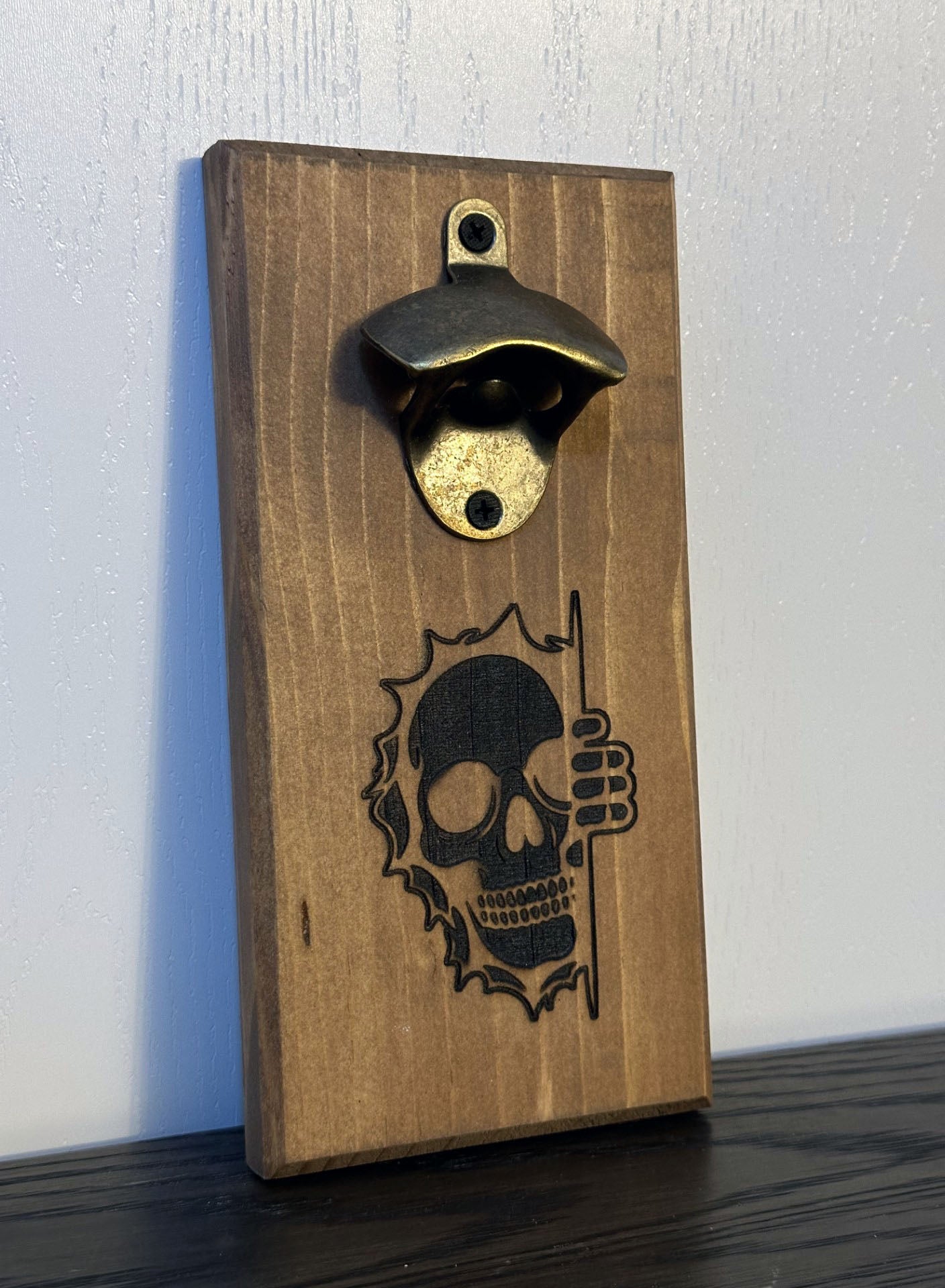 It's spooky season all year long with Mr. Bones peeking around the corner! Each custom magnetic bottle opener is handmade and has hidden rare earth magnets to catch metal bottle caps. Wall-mounted or magnetic backing options. Multiple wood stain choices. Made by Space Rubber Ducky Designs in Southern California, USA.