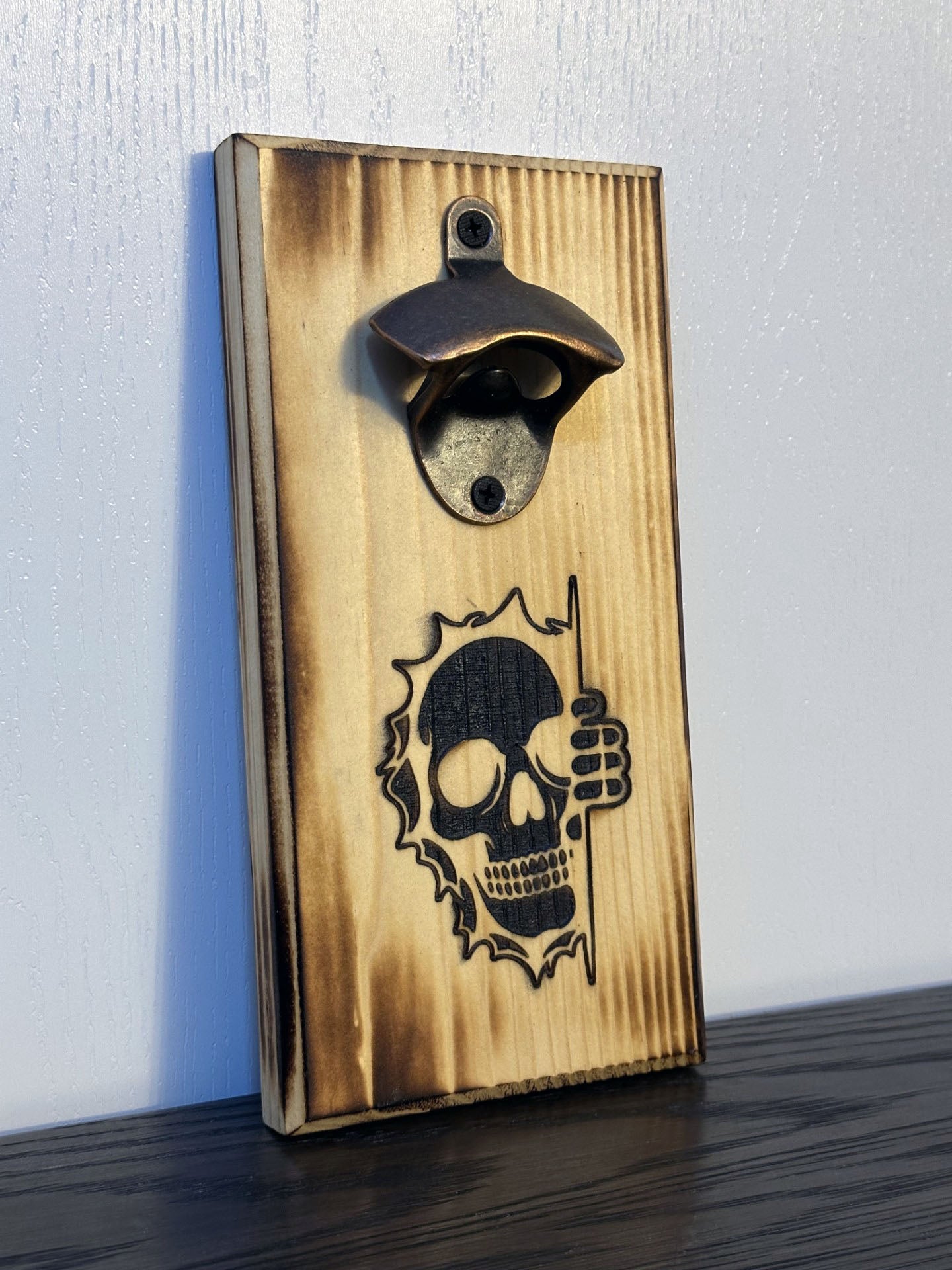 It's spooky season all year long with Mr. Bones peeking around the corner! Each custom magnetic bottle opener is handmade and has hidden rare earth magnets to catch metal bottle caps. Wall-mounted or magnetic backing options. Multiple wood stain choices. Made by Space Rubber Ducky Designs in Southern California, USA.
