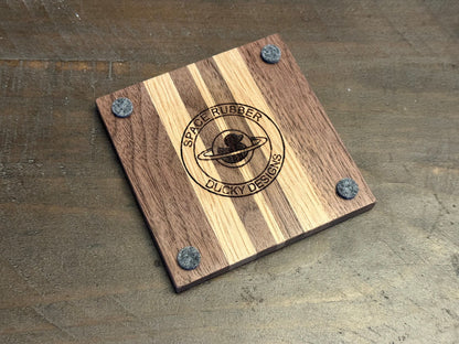 Enjoy a beverage while protecting your tabletops with these walnut and white oak hardwood coasters.  Available in a set of 4 coasters and includes a custom holder.  Each coaster is coated in polyurethane for water resistance and they have felt footpads to protect your surfaces.  As a handmade wood product, there will be slight variation between the product you receive and the listed images.