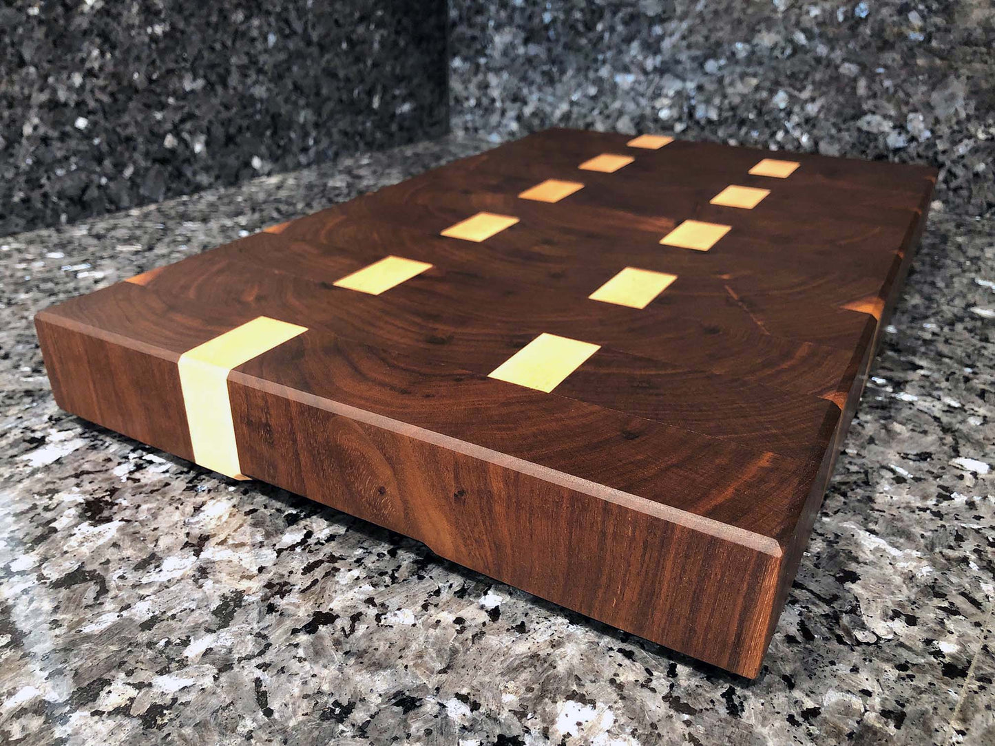 End grain butcher block. Features hardwoods, black walnut with maple accents. Chamfered edges and finger grooves. Hard rubber feet for stability and air circulation.