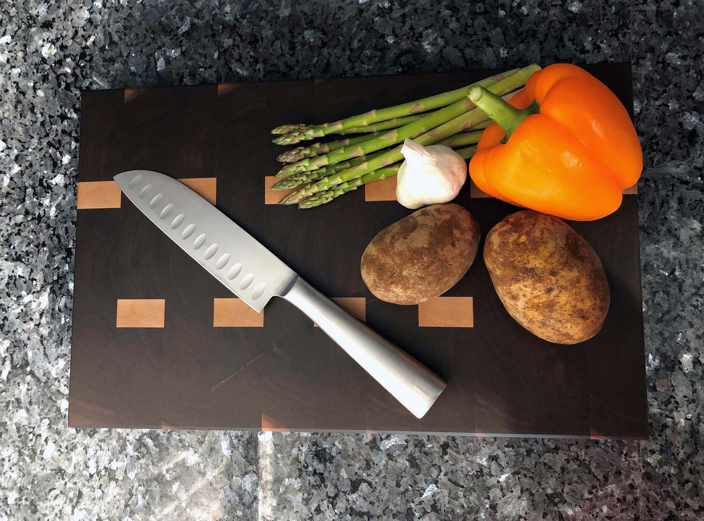 End grain butcher block. Features hardwoods, black walnut with maple accents. Chamfered edges and finger grooves. Hard rubber feet for stability and air circulation.