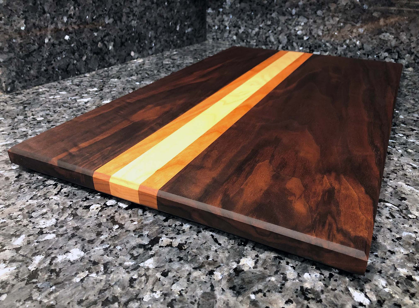 Long grain cutting board. Features black walnut, maple, cherry hardwoods. Chamfered edges and hard rubber feet for stability and air circulation.